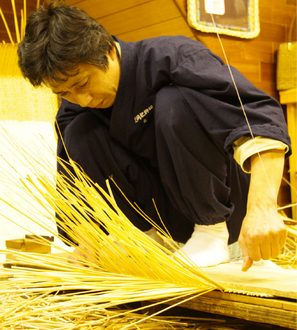 A man weaving wicker to make a bag