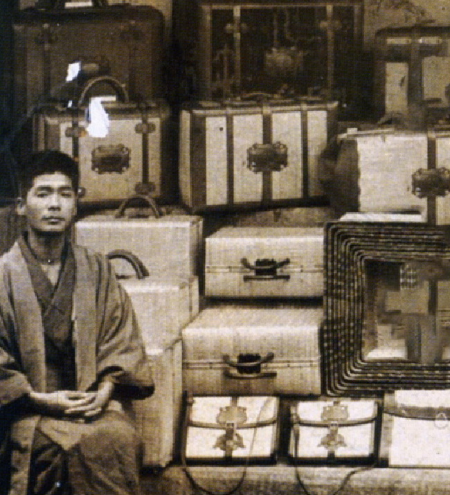 A man sitting next to a pile of Toyooka Kaban traditional wicker bags